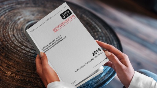 Close-up of a professional's hands holding a 2016 JCT (Joint Contracts Tribunal) Management Building Contract document, illustrating legal documentation in construction management.