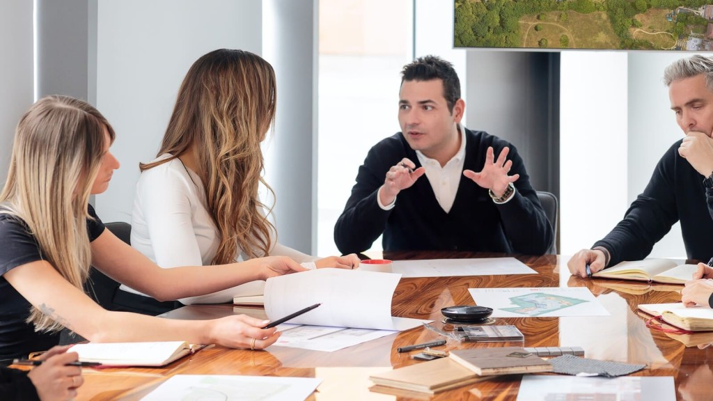 A team discusses development strategy around a meeting table, representing how market intelligence is shaping decisions one year on with Labour in charge and the evolving Grey Belt housing agenda.