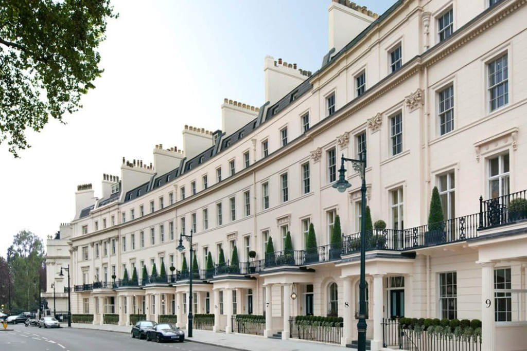 Stately row of cream-colored Georgian houses on a quiet London street, each adorned with decorative railings and manicured window boxes, capturing the elegance of Belgravia's residential architecture.