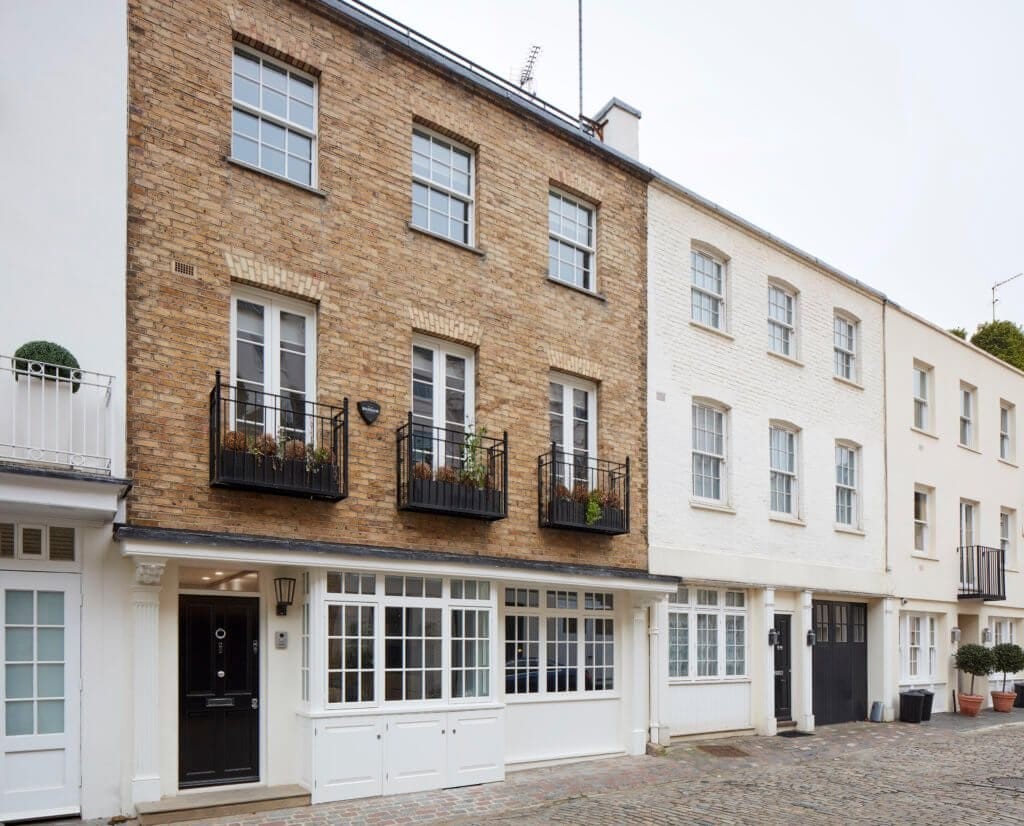 Charming mews houses in Belgravia with classic brick facades, white-framed windows, and Juliet balconies, showcasing traditional London architecture and residential design.