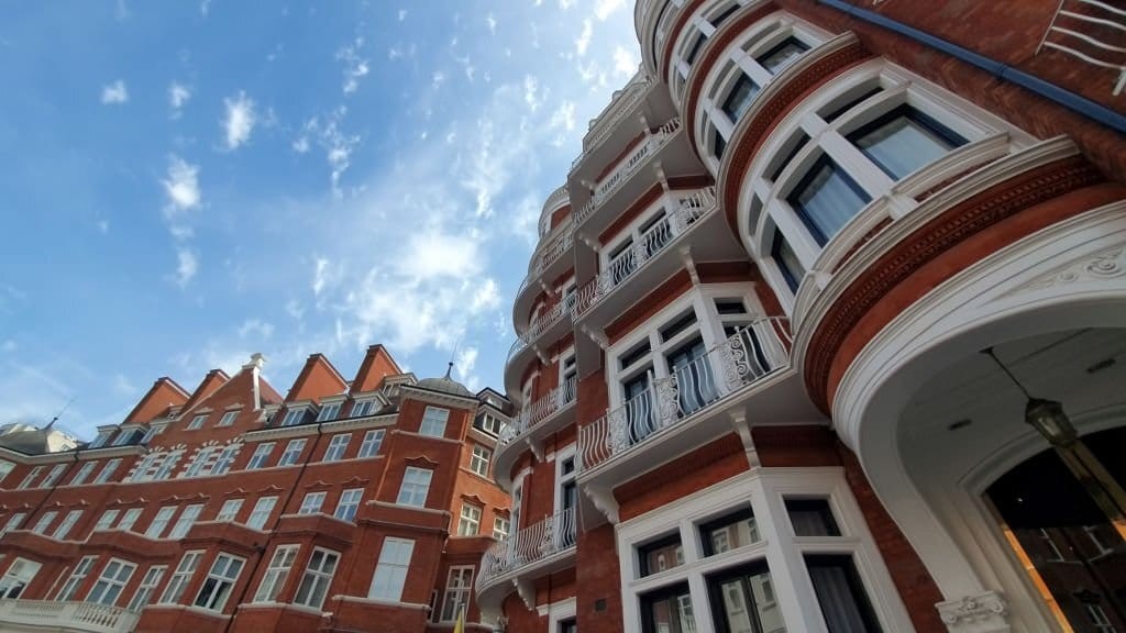 Upward street view of traditional grade ii listed buildings in central London with bright red brickwork and white trimmings around the door entrances, window frames and balcony railings