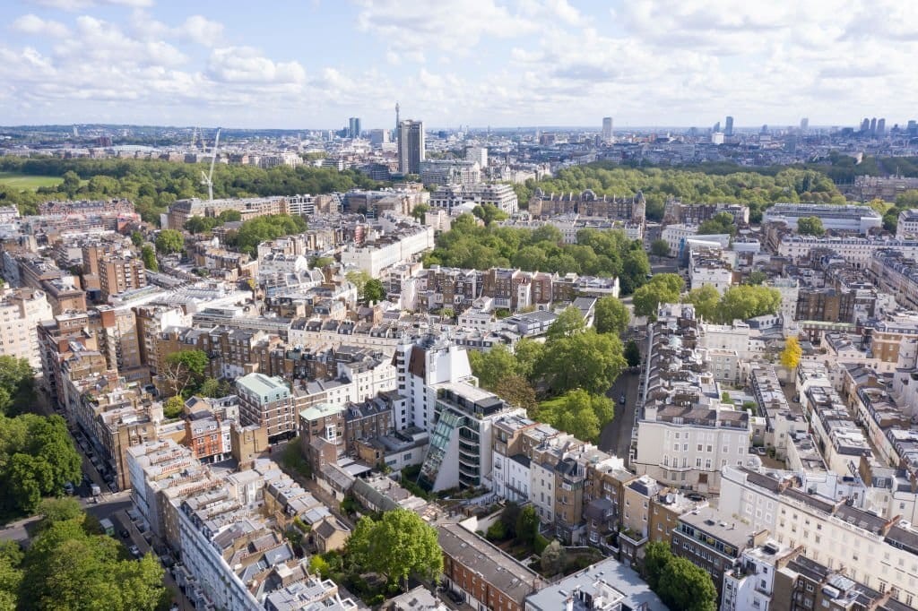 Aerial view on a sunny day of the city with buildings of various heights and architectural style juxtaposed with the luscious green spaces and tall trees
