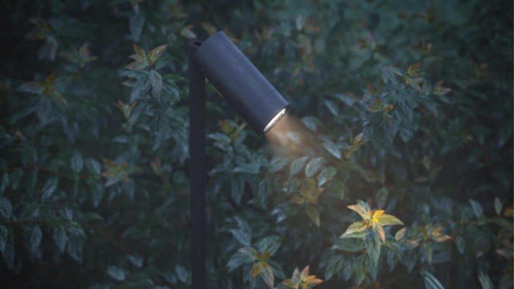 Outdoor garden spotlight with a sleek black design, illuminating the leaves of a lush shrubbery in the evening light.