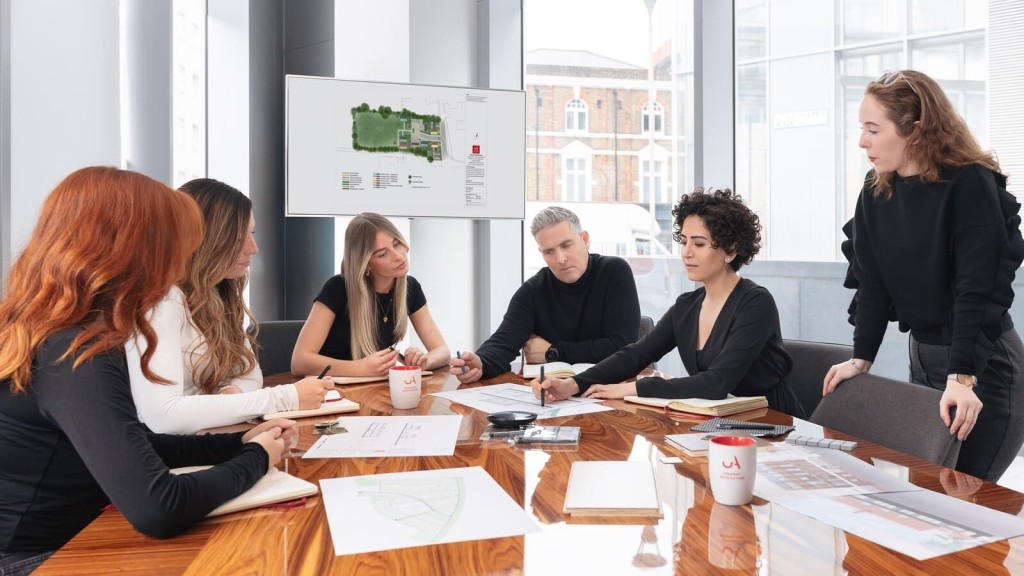 Urban planning team in a design meeting reviewing site layouts and architectural plans, discussing planning permission and strategic development within the Metropolitan Green Belt, in line with the London Plan and potential Green Belt reform policies supported by Mayor Sadiq Khan.
