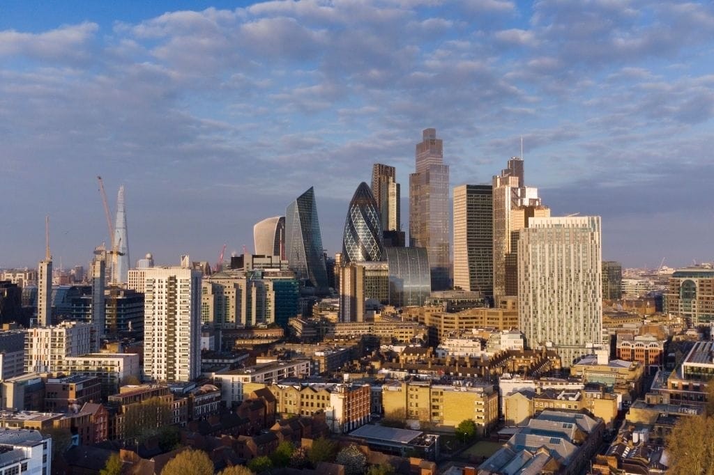 Aerial view of London's skyline at dusk, showcasing a blend of historical buildings and modern skyscrapers under a soft-lit sky, highlighting the city's dynamic architecture and urban planning.