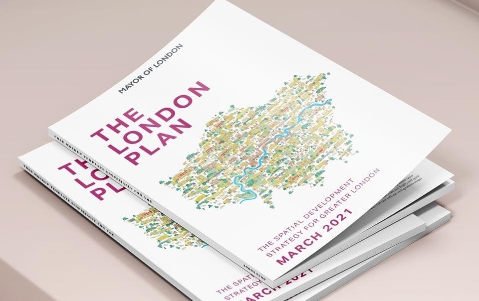 Copies of 'The London Plan March 2021', the spatial development strategy for Greater London by the Mayor of London, with a colorful map of the city on the cover, stacked on a pale pink surface.