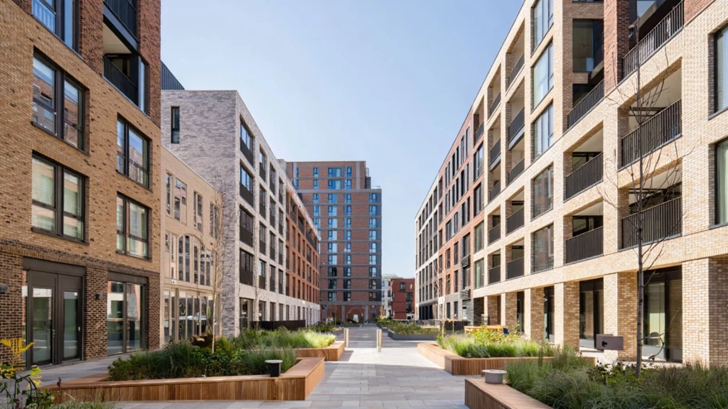 Contemporary brick apartment buildings arranged around a landscaped pedestrian street, illustrating New London Vernacular housing and medium-density urban regeneration in London.
