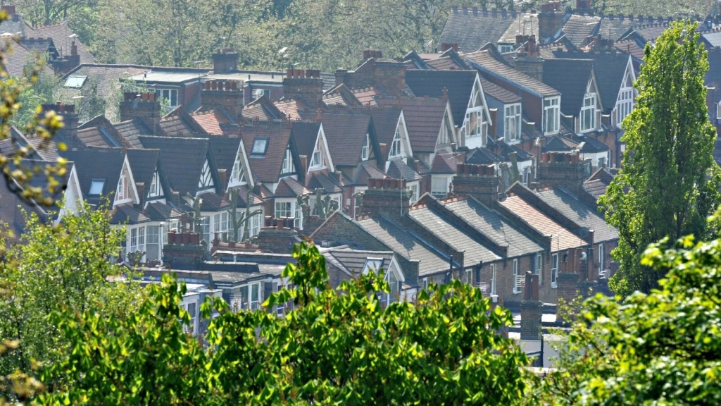 Dense residential neighbourhood of terraced and semi-detached homes surrounded by mature trees and greenery, illustrating how the NPPF 2026 addresses housing development, environmental protection and climate resilience.