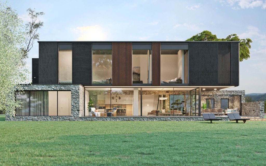 Contemporary countryside home in the late afternoon with mixed materials of wood and stone, featuring large glass windows that reveal a cosy interior and modern furniture on the outside deck, nestled in a tranquil natural setting.