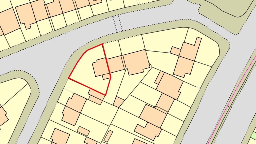 Zoomed-in section of a land registry map highlighting a property boundary in red, surrounded by a residential layout with beige houses and roadways, used for urban planning and property documentation.