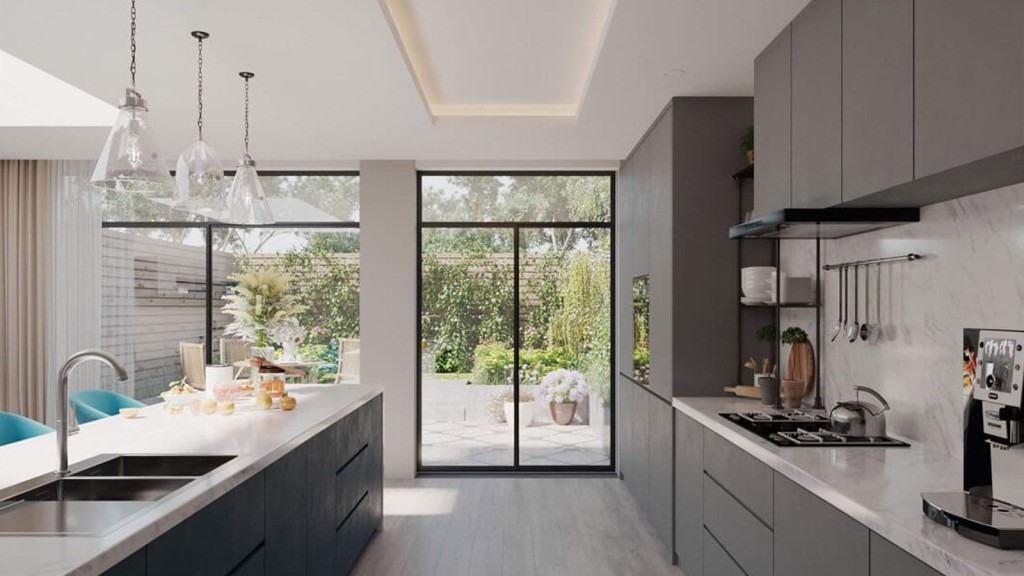 Modern rear kitchen extension design with marble countertops, gray cabinetry, pendant lighting, and a view of a landscaped garden through large sliding glass doors.