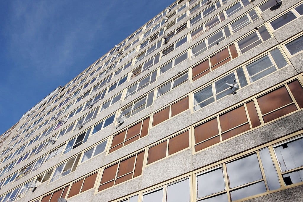 Upward view from the street of a large high rise building of at least 10 storeys and with plenty of natural daylight pouring into the units from the many and large windows