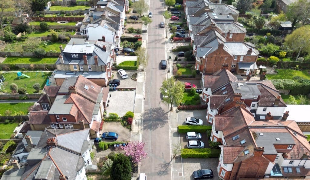 Aerial view of a classic residential street with detached houses, large baywindows at the front, parking bays for two cars per household and long and narrow rear gardens