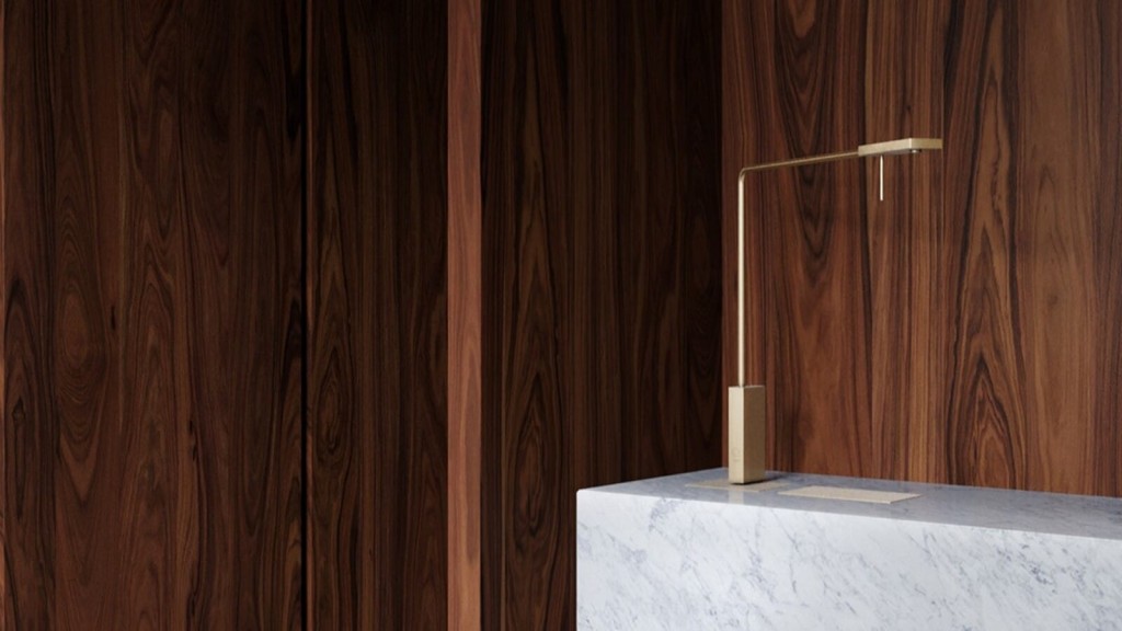 Minimalist interior design featuring a sleek, modern desk lamp on a white marble tabletop against a rich walnut wood panel background, embodying the concept of affordable quiet luxury.