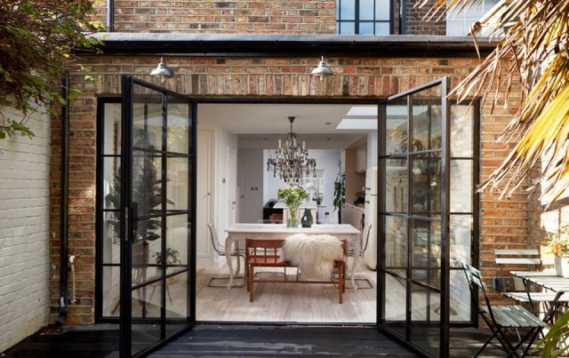 Image cover for the article: Bright and airy kitchen design maximising natural light with large windows and white shutters, featuring a bold blue kitchen island with a yellow countertop, elegant dining area, and chic decorative lighting, ideal for modern home interiors.