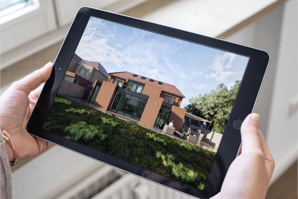 Female client wearing a yellow gold bracelet on her left wrist holding a black iPad horziontally with both hands whilst reviewing architect's renders of the large modern rear extension with large floor to ceiling bifold windows leading directly onto the back patio with furniture and green grass garden 