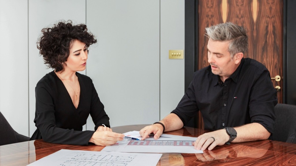 Two professionals in a meeting room discussing architectural plans and building layouts, focusing on key details related to reserved matters for planning approval.