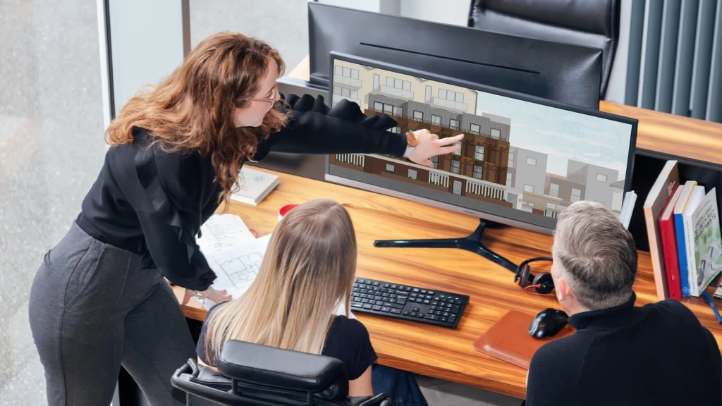 Urbanist Architecture’s multidisciplinary team of residential architects and town planners reviewing their design for a small housing development on screen, discussing building elevations, architectural details and construction implications.