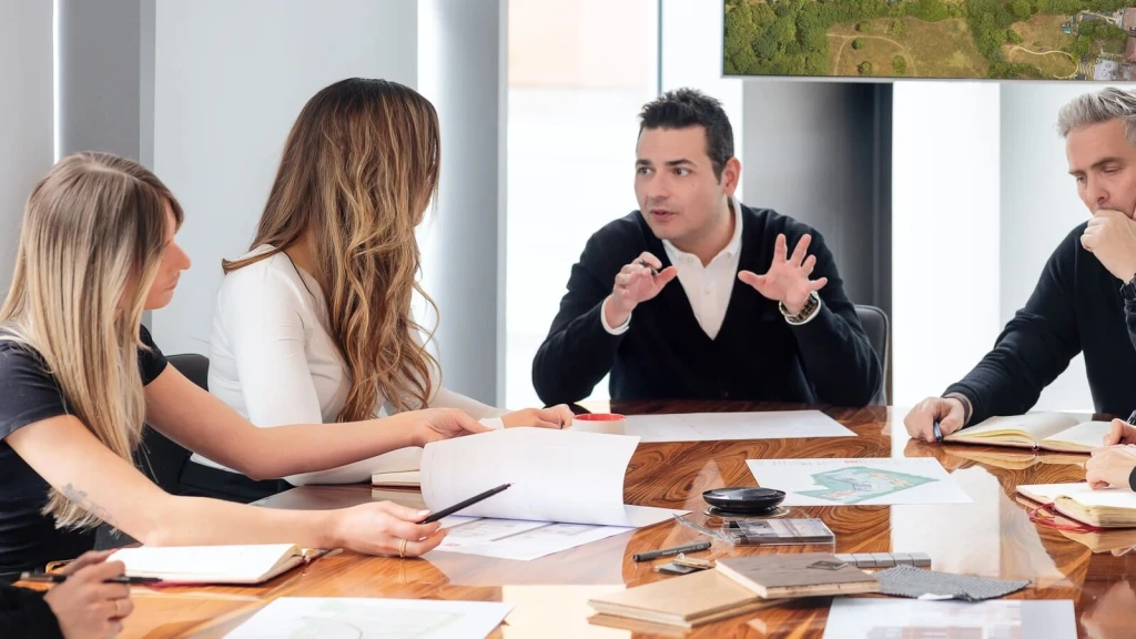 Urbanist Architecture Managing Director Ufuk Bahar discussing a residential planning application with the practice’s team of architects and town planners, reviewing drawings and supporting documents around a meeting table.