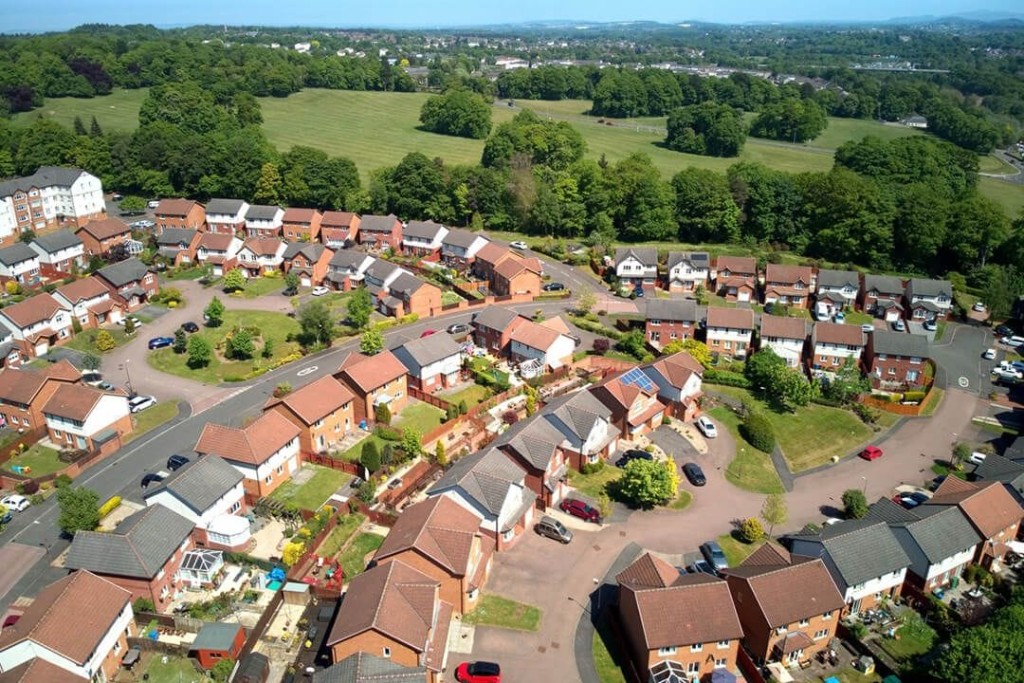 Aerial view of a suburban neighborhood with neat rows of houses and green lawns, showcasing community planning and residential architecture on a sunny day.