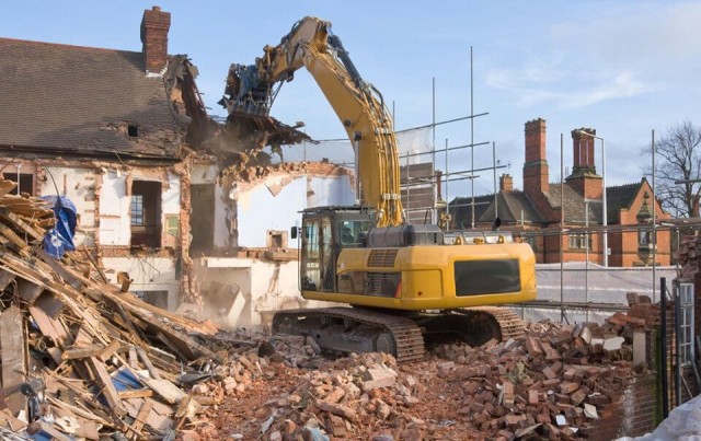 Image cover for the article: Skills builder carrying a silver ladder on his shoulder and wearing an orange hi-vis, white hard hat and yellow protective gloves walking through a construction site with only timber pillars installed as the framework of the internal layout