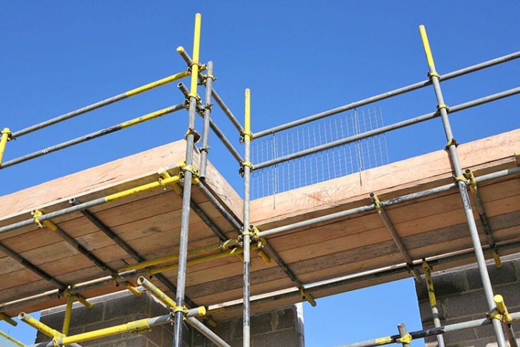 Construction scaffolding with yellow clamps on a clear day, highlighting building safety and renovation work.