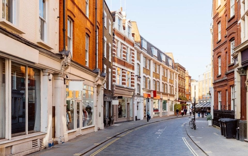 Quiet street in an English town lined with traditional brick buildings and shopfronts, highlighting potential for shop to residential conversions under new Class E to residential (C3) development rights.