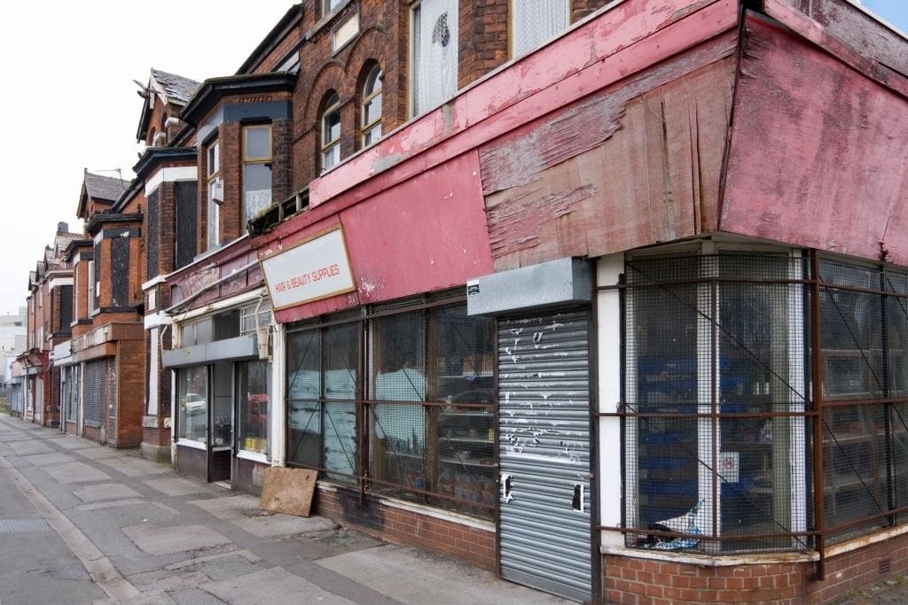 A row of dilapidated and boarded-up shops with worn-out signage and shuttered windows, highlighting the potential for shop to residential conversions under new permitted development rights in England aimed at revitalising neglected high streets.