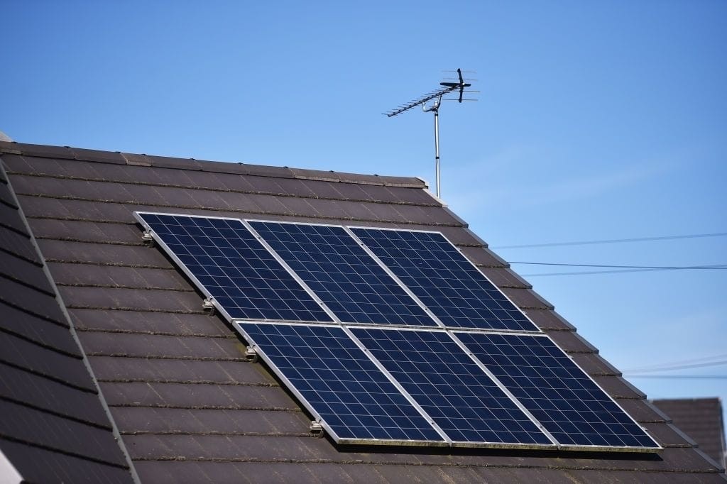 Solar panel mounted on a residential rooftop with clear blue sky, depicting renewable energy solutions for sustainable home renovation and eco-friendly living.