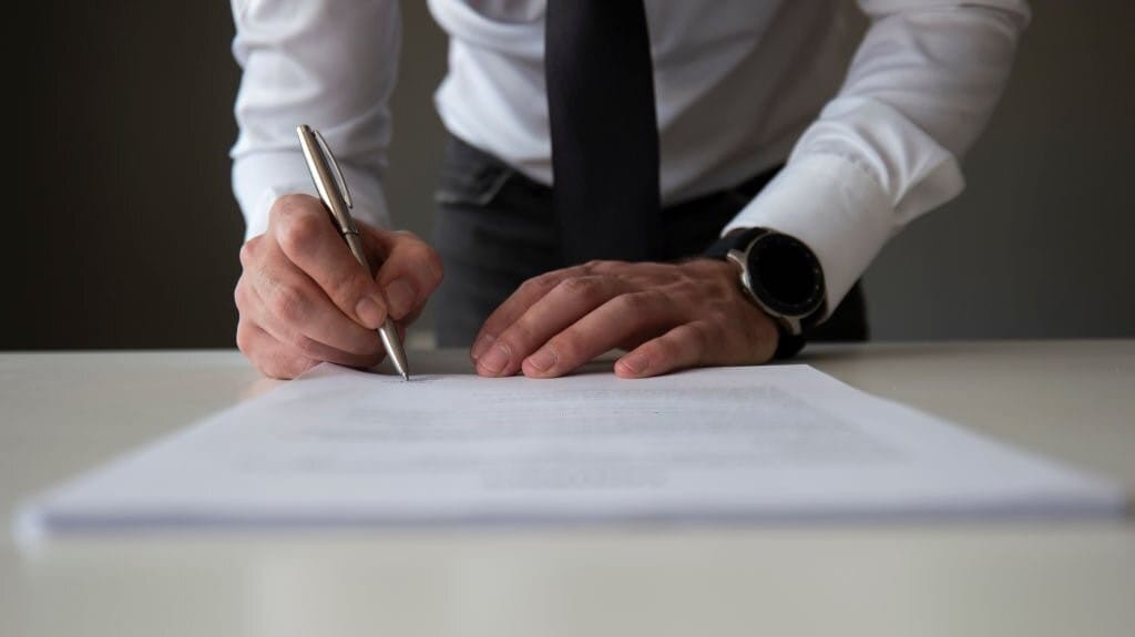 Close-up of a businessman's hands signing a contract with a silver pen, showcasing professionalism and commitment in a corporate environment.