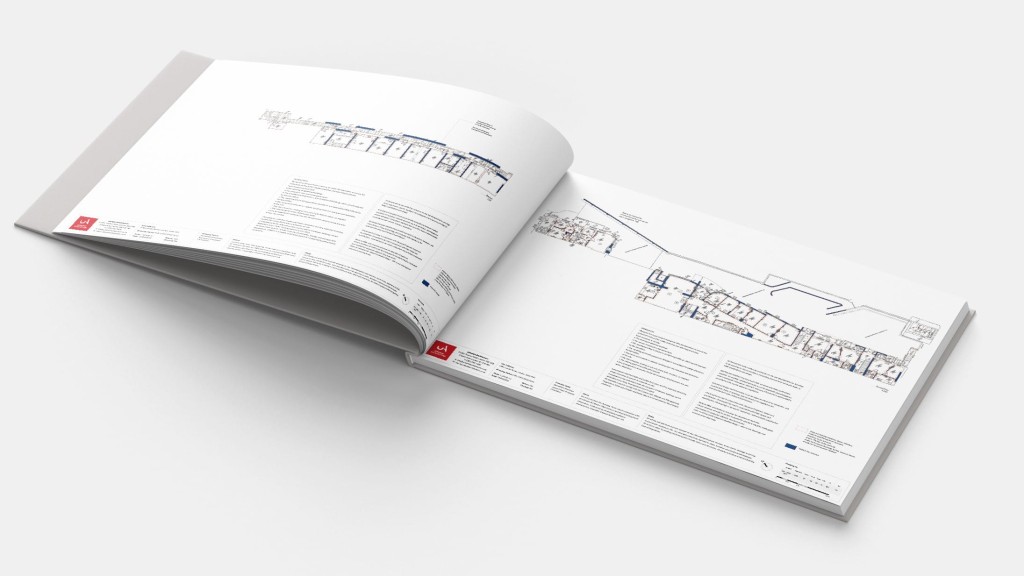 Open architectural magazine featuring detailed building plans and text descriptions, lying on a flat surface with a focus on design and layout.