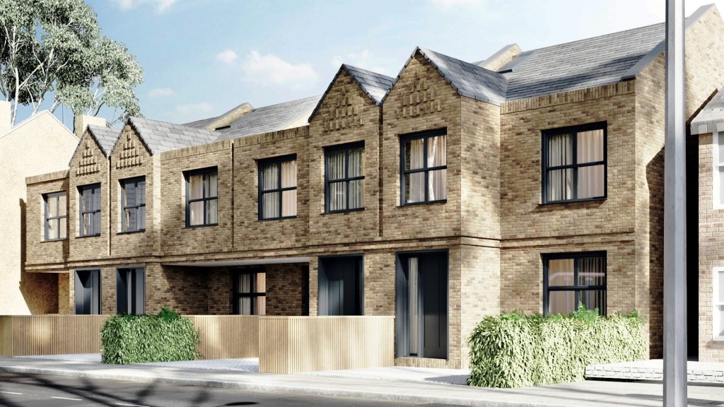 Newly constructed terraced houses with distinctive gable roofs and brick facades on a sunny day, showcasing modern urban architecture.