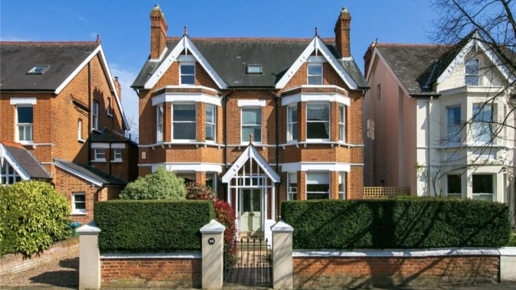 Victorian detached children’s home in London with red brick façades, bay windows, gabled roof details and front garden hedging.