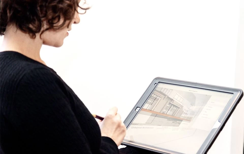 Architect reviewing a digital building model on a tablet, demonstrating how AI-powered planning software, digital planning applications and architectural design technology can support faster planning decisions and streamlined development approvals.