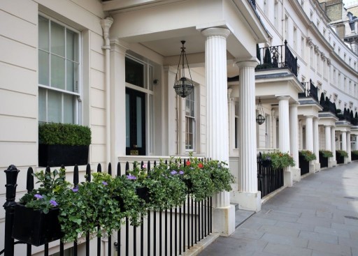 Side view of a traditional late Georgian and Regency property in Belgravia with lovely hanging pots of flowers on the front railing. 