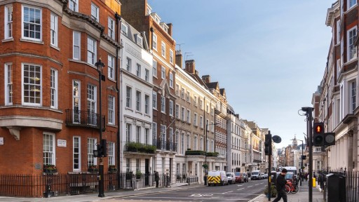 Classic street view of Central London featuring a row of traditional red-brick and white facade buildings, highlighting the city's iconic blend of historical and contemporary architecture.