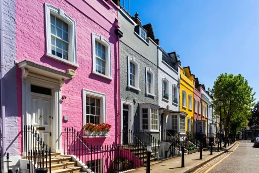 Row of brightly coloured bink, grey, white, yellow and peach terrace houses that can be found in various streets of Chelsea such as Lennox Gardens Mews or Markham Street