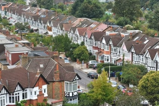 Rows of distinctive terraced houses with pointed roofs in Ealing, London, demonstrating the classic British residential architecture lined along a leafy suburban street.