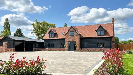 Newly built traditional Essex-style house with a brick and black timber exterior, featuring a spacious driveway and landscaped garden.