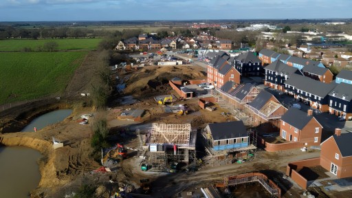 A bustling construction site in Essex with various stages of housing development, from foundations to completed structures, showcasing the growth and development of new residential areas.