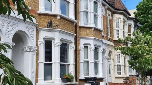 Row of beautiful terrace houses with ornate entrance door frames and white or cream bay window pillars