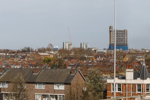 View of Havering's urban landscape showing a mix of residential houses with gabled roofs and modern high-rise buildings under construction against a cloudy sky.