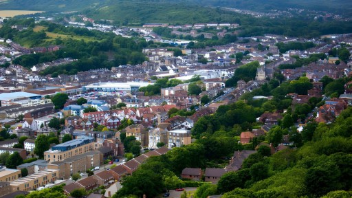 Aerial view of Kent's vibrant landscape showing the diverse architecture with residential homes, commercial buildings, and the lush greenery of the surrounding hills, highlighting the unique charm of this English county.