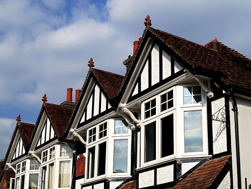 Photograph of a row of pitched roof terrace houses with a Tudor mock design above the front upper window bays