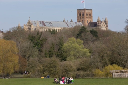 Families gathered on the luscious green grass and dense trees at the rear of St Albans Cathedral
