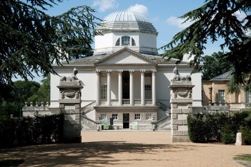 Pebbled entrance view of Chiswick House, a Neo-Palladian style villa surrounded by a vibrant and green garden