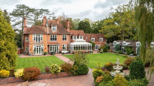 Elegant traditional brick house in West Midlands with large windows, a conservatory, and lush landscaped garden, showcasing popular home improvement projects and quintessential English residential architecture.