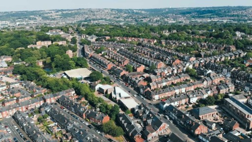 Aerial view of Wimbledon residential area with rows of Victorian terraced houses, lush green trees, and clear roadways on a bright sunny day, highlighting the charming urban layout and community atmosphere of the suburb.