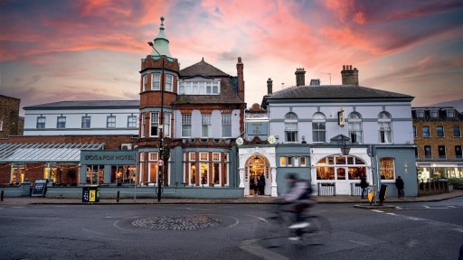 Twilight over Wimbledon Village with the historic Dog & Fox Hotel, featuring classic British architecture under a dramatic pink and orange sky, capturing the quaint and traditional charm of the area.