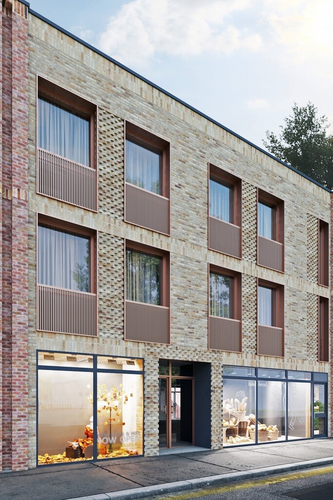 Exterior view of a modern new-build flats development in London, showcasing contemporary brick facade with large windows and retail spaces on the ground floor. This image highlights urban residential architecture with a focus on high-quality materials and design, perfect for maximising ROI and achieving commercial viability in housing projects.